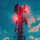 Une tour de télécommunication avec plusieurs antennes et des lumières rouges sur fond de ciel partiellement nuageux.